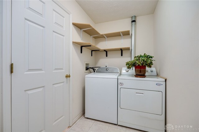 laundry area with washing machine and dryer, light tile patterned flooring, and a textured ceiling