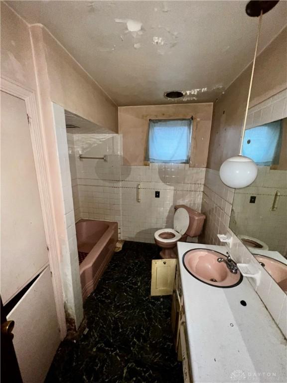 bathroom with vanity, tile walls, and toilet