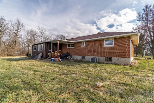 rear view of house featuring central AC and a yard