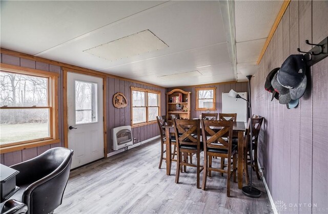 dining room featuring heating unit, wood walls, and light hardwood / wood-style flooring