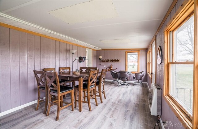 dining room featuring hardwood / wood-style flooring, heating unit, and wooden walls