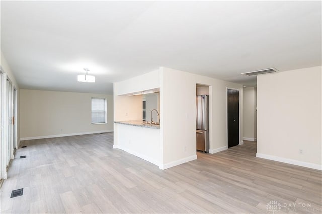 unfurnished living room with light wood-type flooring and sink