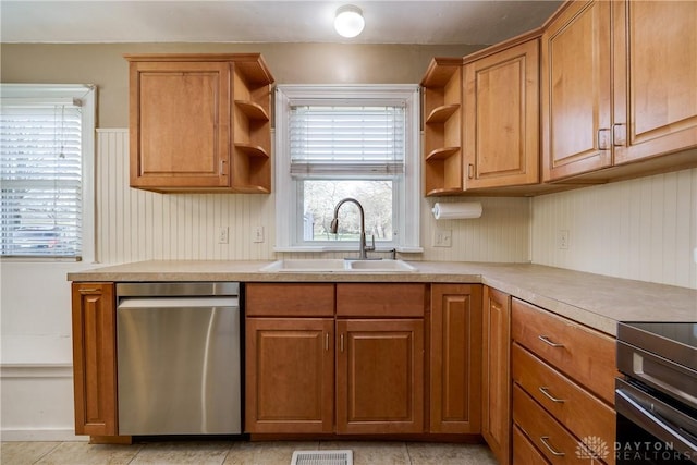 kitchen featuring dishwasher, light tile patterned floors, sink, and range