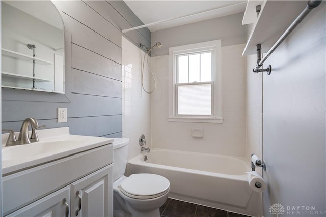 full bathroom with tiled shower / bath combo, tile patterned flooring, wood walls, toilet, and vanity