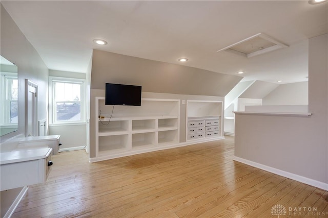 bonus room featuring built in shelves, light wood-type flooring, and lofted ceiling