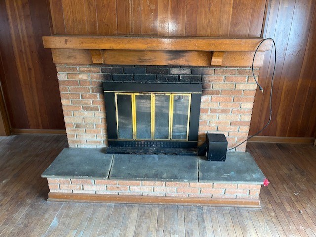 details with a brick fireplace and wooden walls