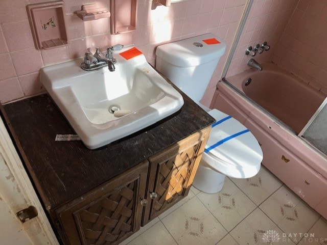 full bathroom featuring backsplash, toilet, tile walls, and combined bath / shower with glass door