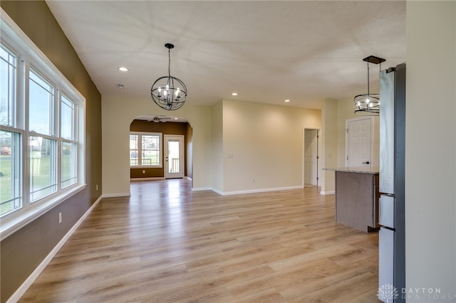 empty room with light wood-type flooring and an inviting chandelier