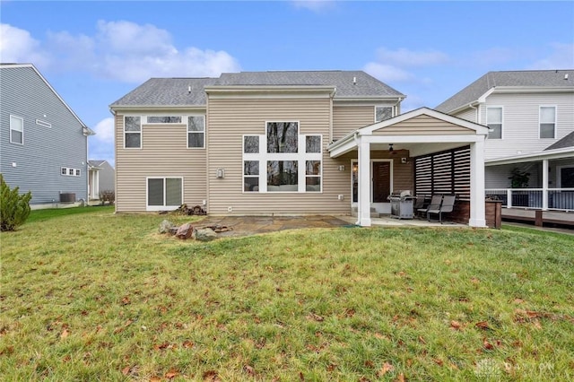 rear view of property featuring central AC unit, ceiling fan, a patio area, and a lawn