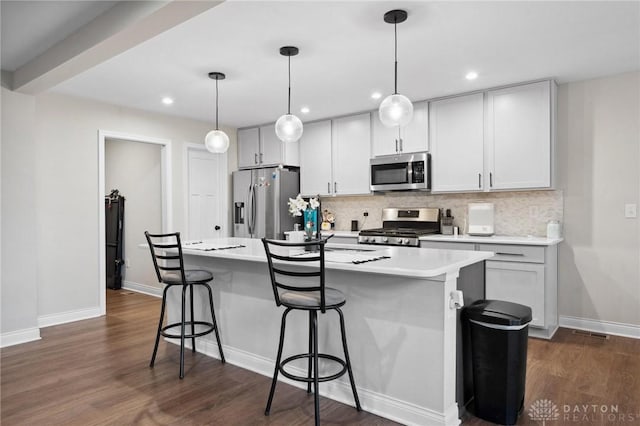 kitchen with appliances with stainless steel finishes, a kitchen breakfast bar, pendant lighting, and an island with sink