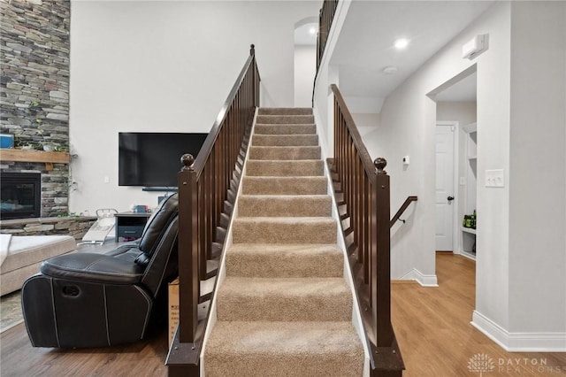 stairway featuring a stone fireplace and wood-type flooring