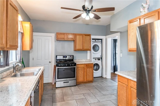 kitchen featuring ceiling fan, stacked washer / dryer, sink, and appliances with stainless steel finishes