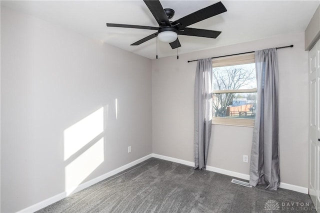 empty room featuring ceiling fan and dark carpet