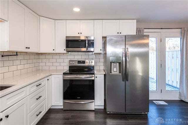 kitchen featuring backsplash, white cabinets, stainless steel appliances, and dark hardwood / wood-style floors