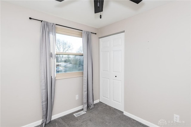 unfurnished bedroom featuring ceiling fan, a closet, and dark colored carpet