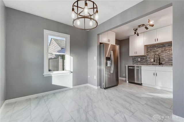 kitchen featuring sink, hanging light fixtures, stainless steel appliances, tasteful backsplash, and white cabinets