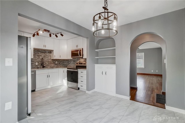 kitchen with appliances with stainless steel finishes, backsplash, decorative light fixtures, and white cabinetry