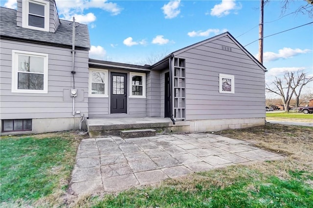 view of exterior entry with a lawn and a patio