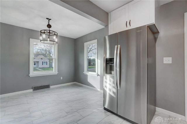 kitchen featuring white cabinetry, hanging light fixtures, stainless steel refrigerator with ice dispenser, and an inviting chandelier