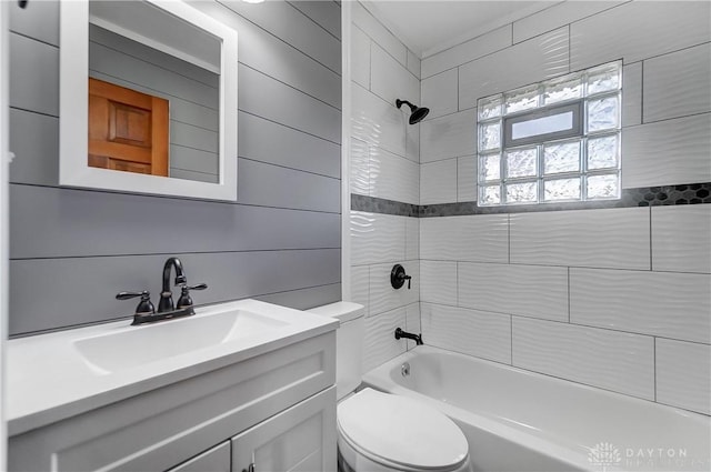 full bathroom featuring tiled shower / bath combo, wood walls, toilet, and vanity