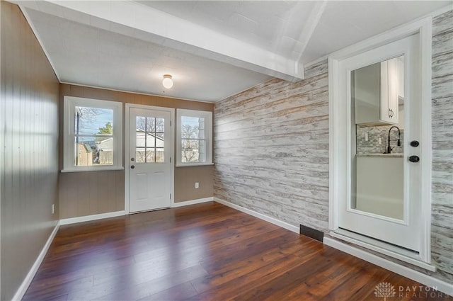 doorway to outside with beam ceiling, dark hardwood / wood-style flooring, and wooden walls