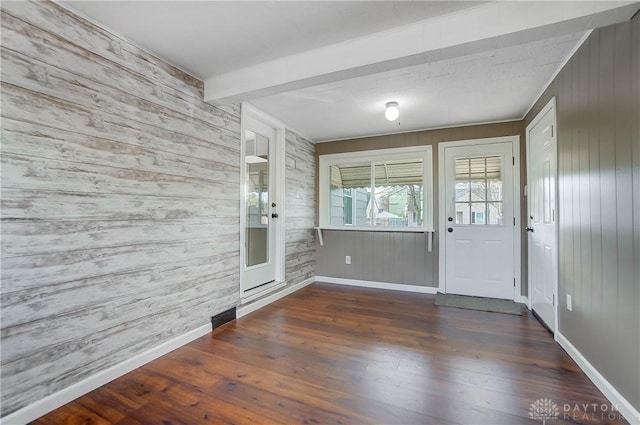 doorway featuring beamed ceiling, wood walls, and dark wood-type flooring