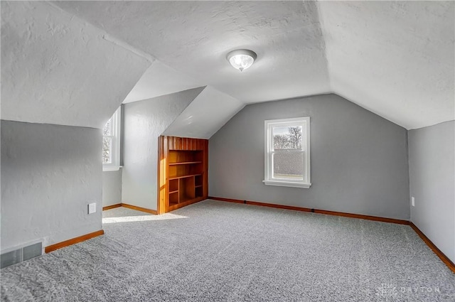 bonus room with a textured ceiling, carpet floors, and lofted ceiling