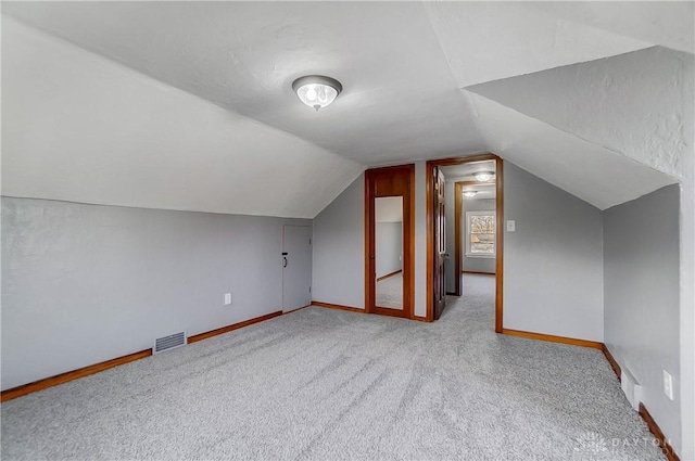 bonus room with light colored carpet and vaulted ceiling