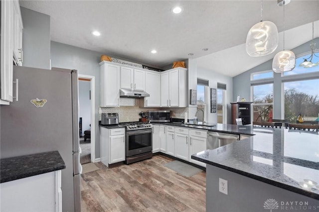 kitchen with sink, white cabinets, stainless steel appliances, and decorative light fixtures