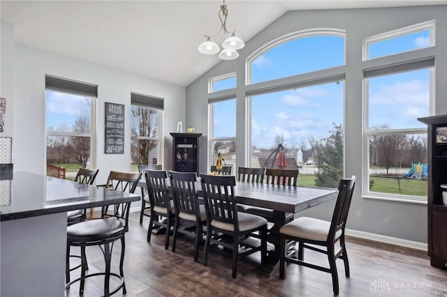 dining space with dark hardwood / wood-style flooring, vaulted ceiling, and an inviting chandelier