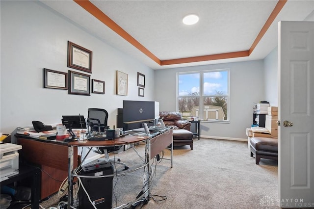 carpeted office space with a tray ceiling