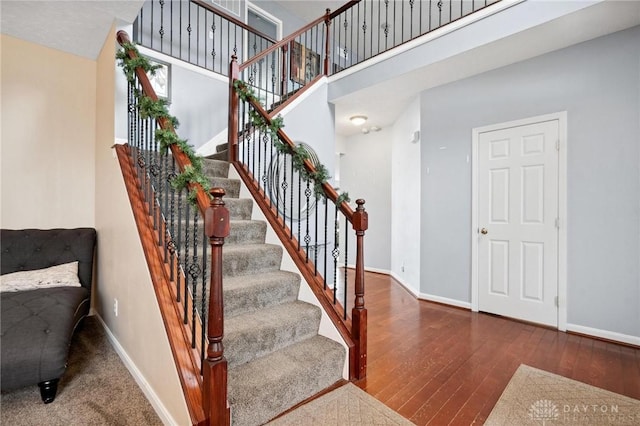 stairway with hardwood / wood-style floors and a high ceiling