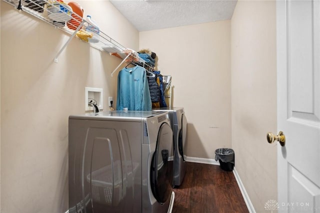 washroom with dark hardwood / wood-style flooring, washing machine and dryer, and a textured ceiling