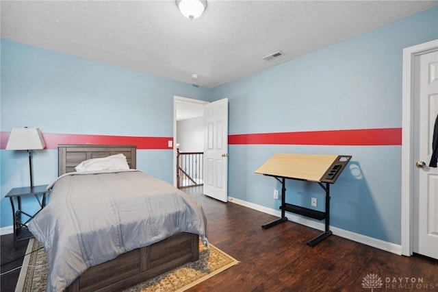 bedroom with dark hardwood / wood-style flooring and a textured ceiling