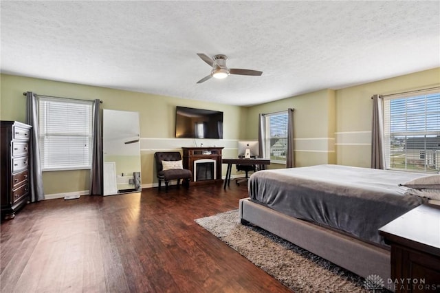 bedroom with a textured ceiling, ceiling fan, and dark hardwood / wood-style floors