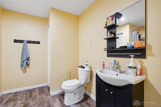 bathroom with wood-type flooring, vanity, and toilet