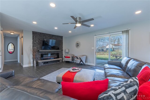 living area with baseboards, a stone fireplace, and recessed lighting