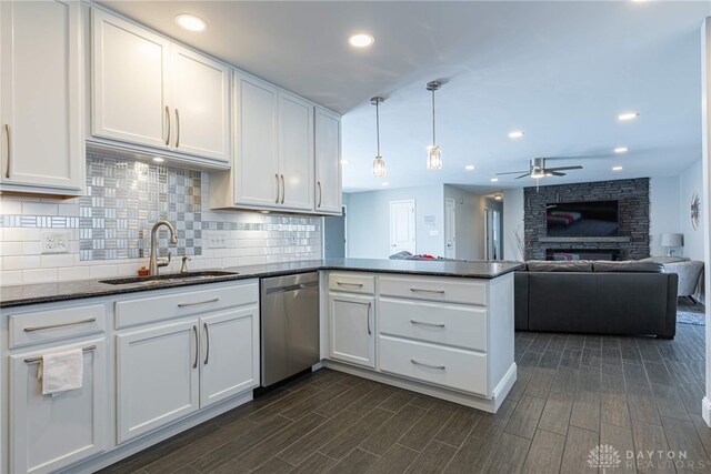 kitchen with a peninsula, a sink, white cabinetry, stainless steel dishwasher, and decorative backsplash