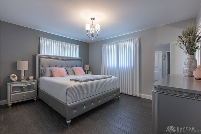 bedroom featuring dark wood-style floors, baseboards, and an inviting chandelier