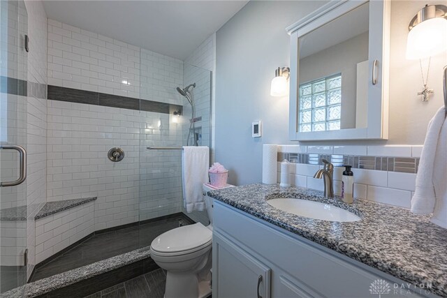 bathroom with toilet, a shower stall, and vanity