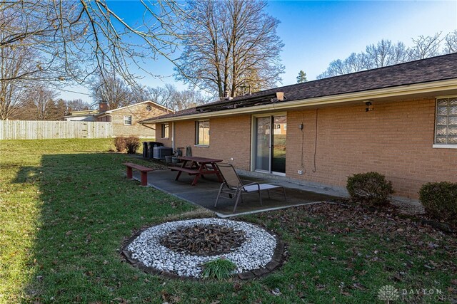 rear view of house featuring a yard, brick siding, fence, and a patio