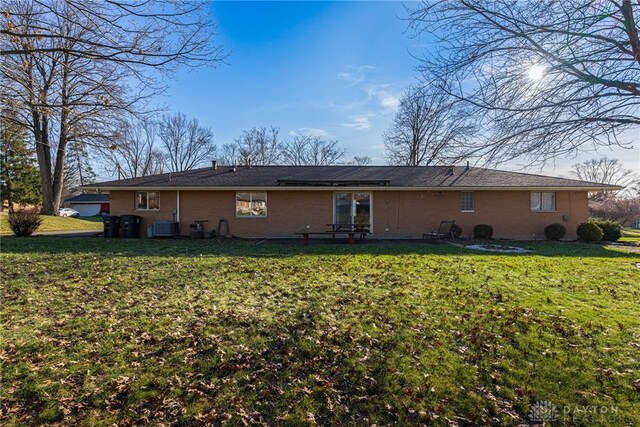 back of house featuring a yard, central AC unit, and brick siding