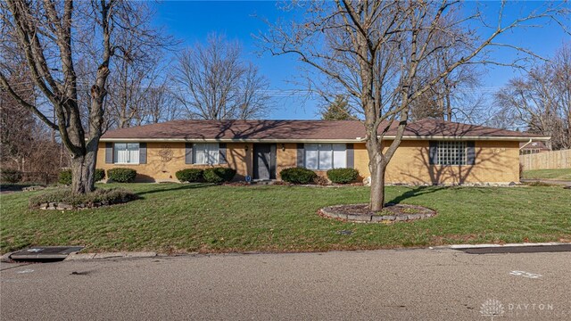 single story home featuring brick siding, fence, and a front yard