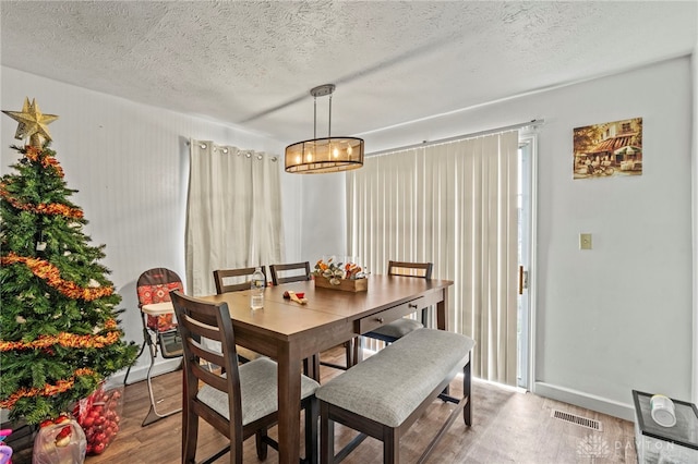 dining area with hardwood / wood-style floors and a textured ceiling