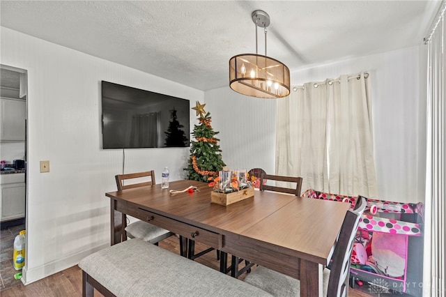 dining space featuring wood-type flooring, a textured ceiling, and an inviting chandelier