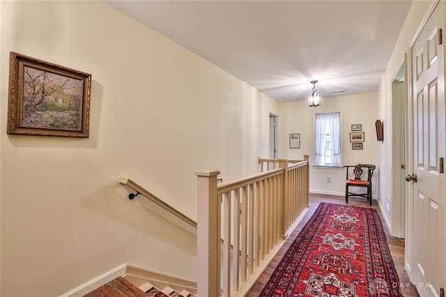 hallway featuring hardwood / wood-style floors and a chandelier