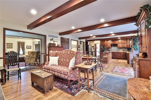 living room featuring beamed ceiling and light hardwood / wood-style flooring