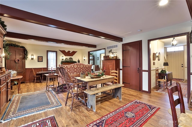 dining space with beamed ceiling and light wood-type flooring