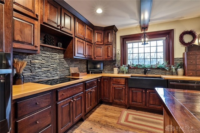 kitchen featuring tasteful backsplash, wooden counters, light hardwood / wood-style floors, and black appliances