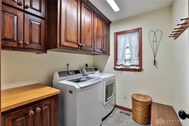 clothes washing area featuring separate washer and dryer and cabinets